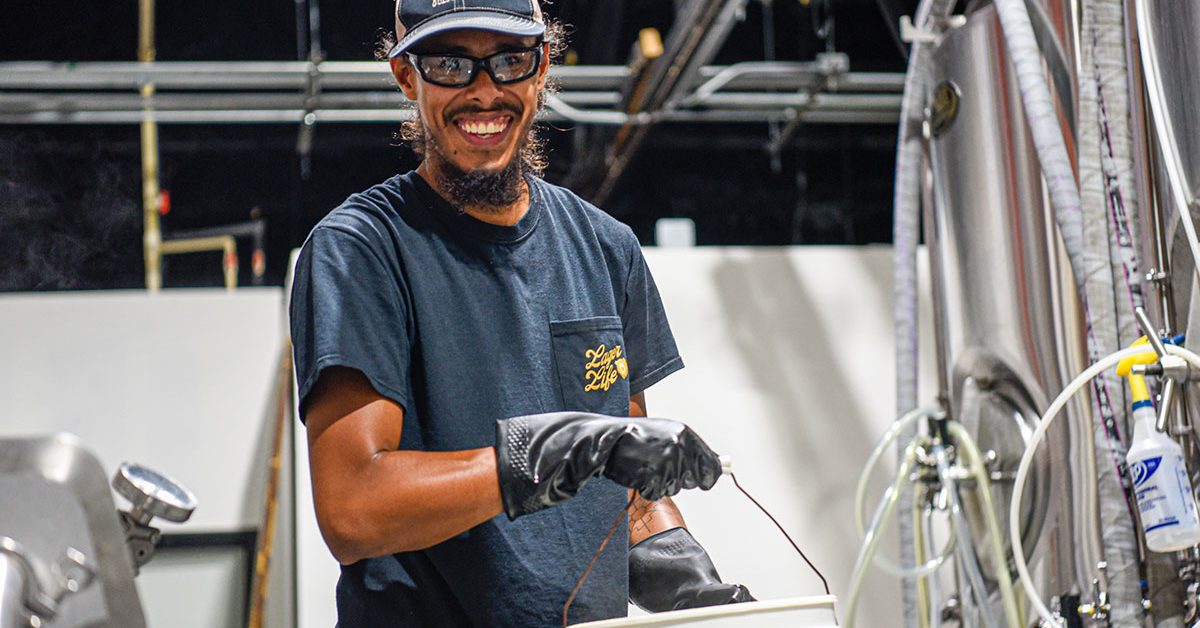 smiling man carrying bucket in a brewhouse