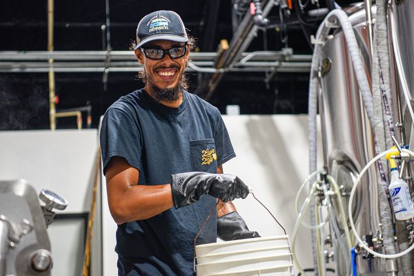 smiling man carrying bucket in a brewhouse