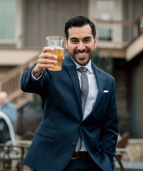 man dressed in a suit holding out a beer