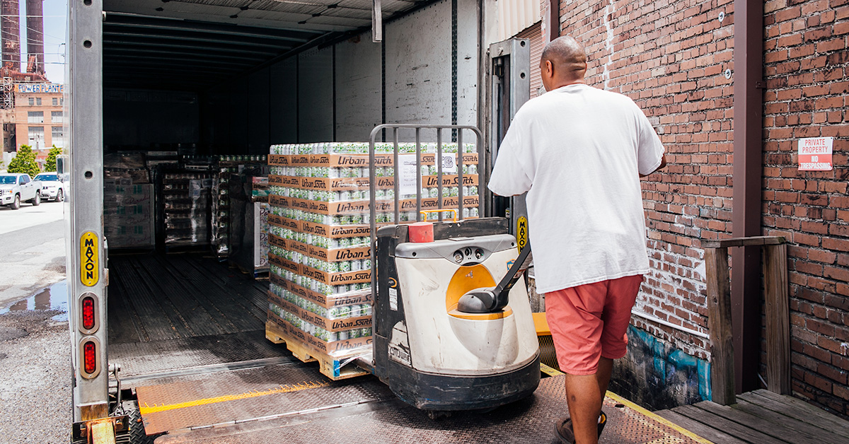 man loading packaged beer into truck for distribution 1200x628 1