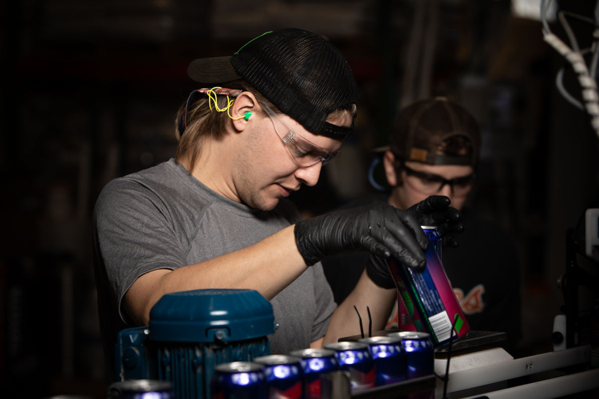 man working canning line wearing ear and eye protection