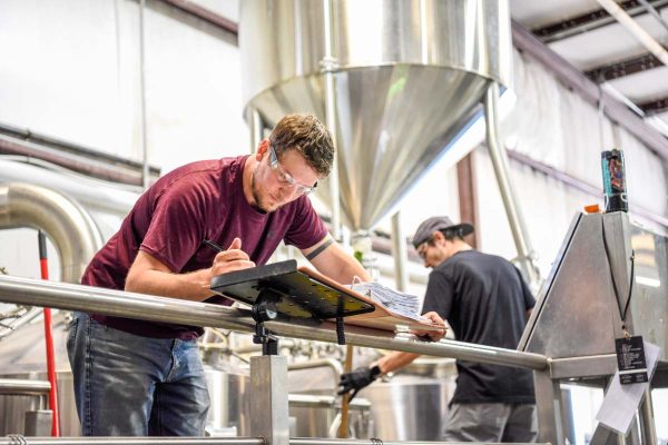 Person in brewery writing in binder