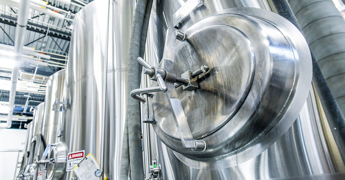 row of fermenters in craft brewery 1200x628 1