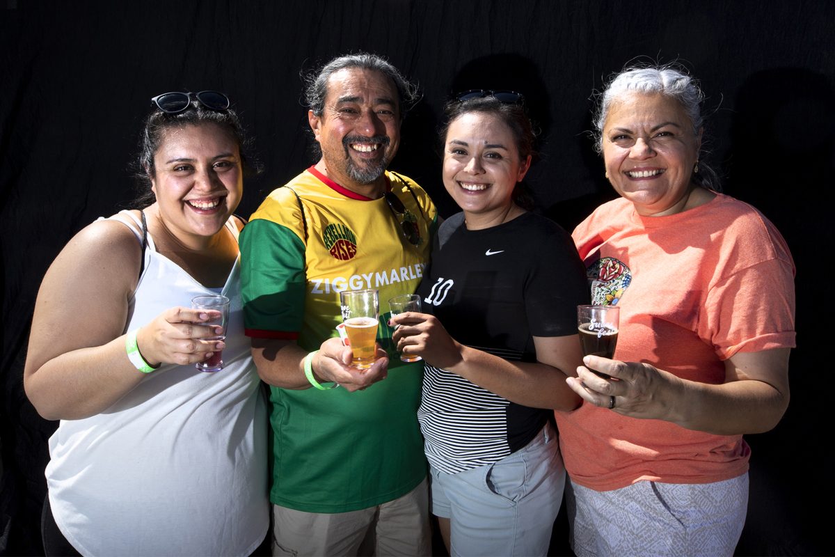 Three women and one man holding beer and smiling.