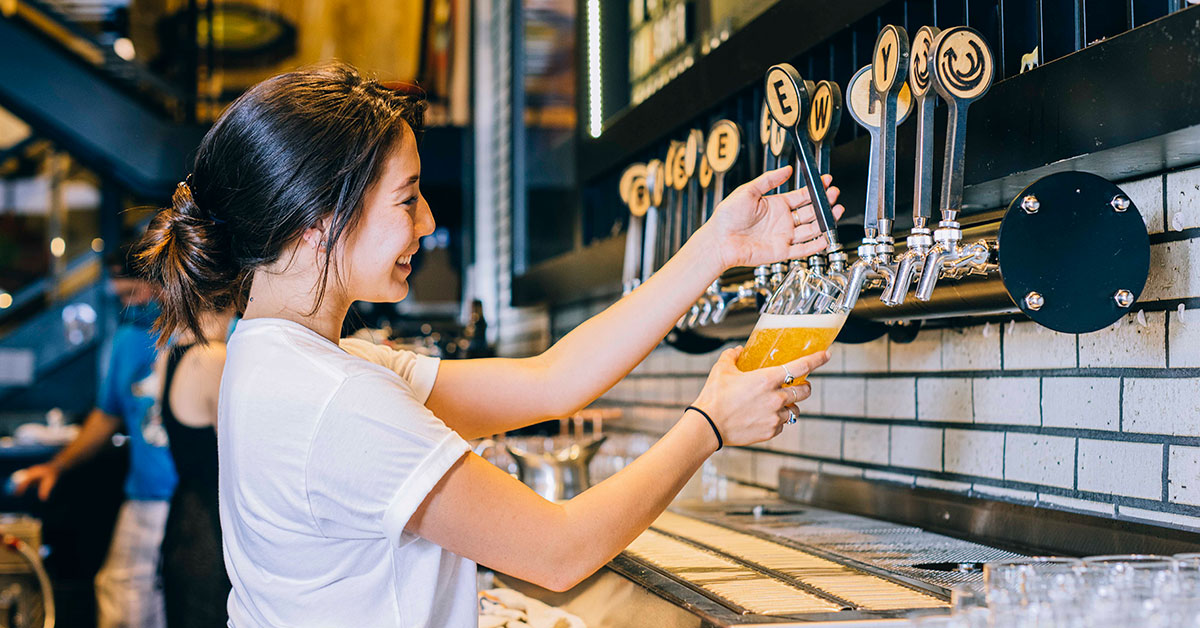 woman pouring draught beer in taproom x