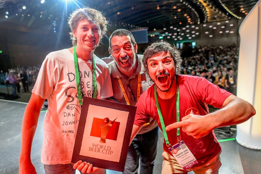 Three excited men holding a trophy at the world beer beer cup awards ceremony