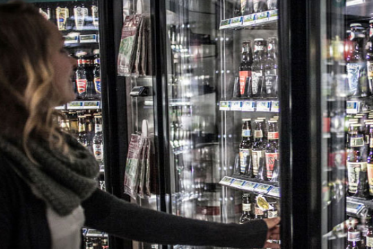 woman selecting craft beer from retailer